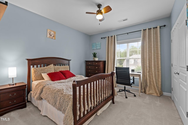 bedroom featuring light colored carpet, an office area, a ceiling fan, baseboards, and a closet