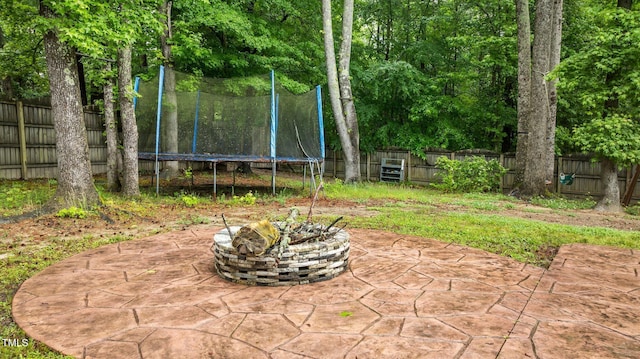 view of patio / terrace with a trampoline, a fire pit, and a fenced backyard