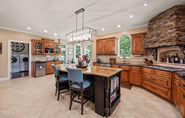 53 Lake Wendell Rd, Wendell, NC 27591 - kitchen with washer and clothes dryer, appliances with stainless steel finishes, a kitchen island, decorative backsplash, and brown cabinetry