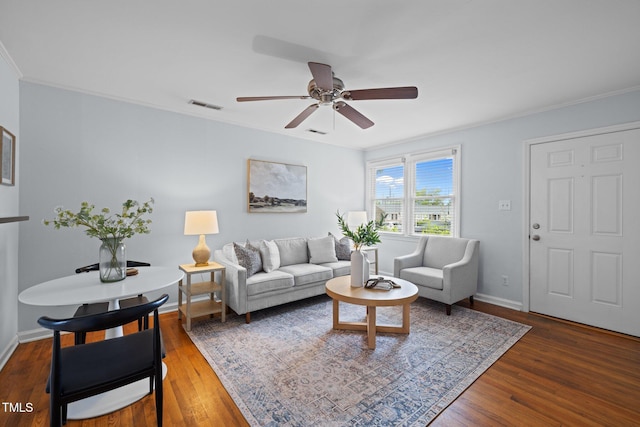 living room featuring wood finished floors, ceiling fan, ornamental molding, and baseboards