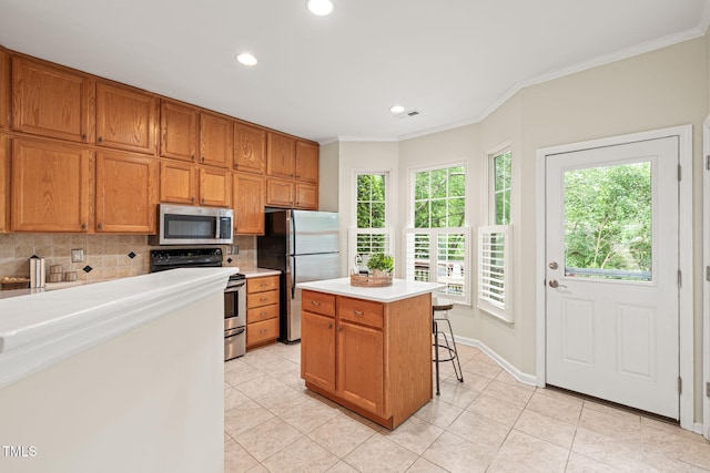 kitchen featuring appliances with stainless steel finishes, backsplash, light tile patterned flooring, light countertops, and crown molding