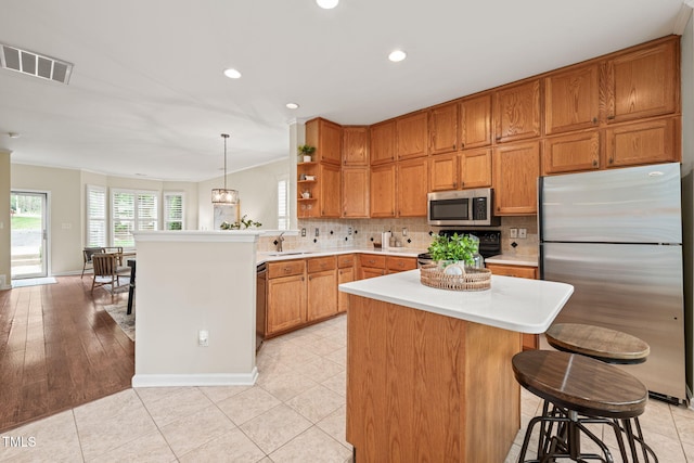 kitchen featuring stainless steel appliances, a peninsula, light countertops, backsplash, and recessed lighting