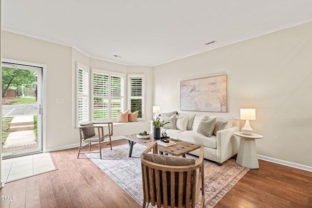 living area featuring wood finished floors, crown molding, and baseboards