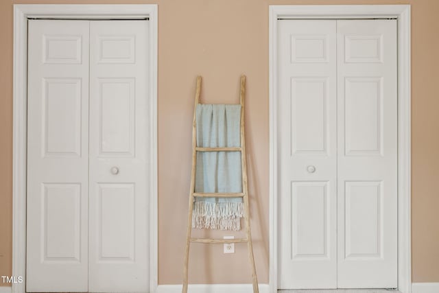 bedroom with baseboards and two closets