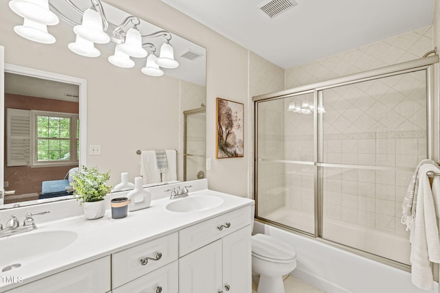 ensuite bathroom featuring double vanity, enclosed tub / shower combo, and toilet