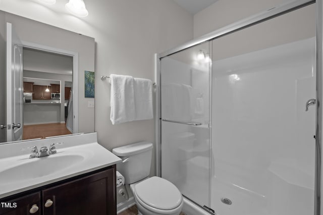 bathroom with a stall shower, toilet, and vanity