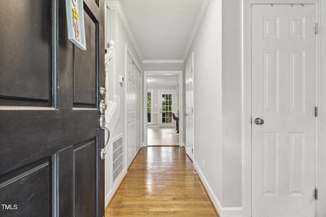 hallway with light wood-type flooring, crown molding, and baseboards