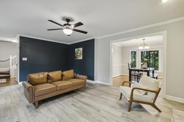 living area with light wood-style flooring, crown molding, baseboards, and a chandelier
