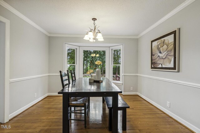 dining area with a chandelier, wood finished floors, crown molding, baseboards, and a textured ceiling