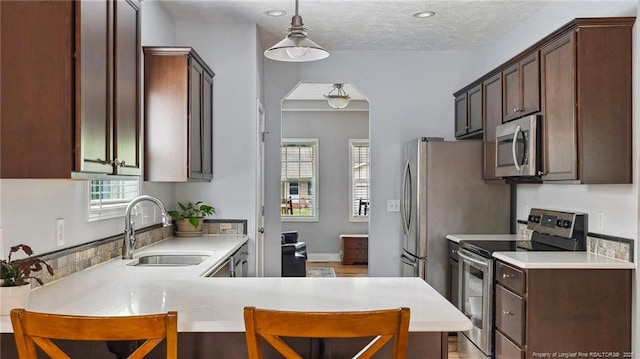 116 Argyll Ave, Aberdeen, NC 28315 - kitchen featuring stainless steel appliances, a sink, light countertops, hanging light fixtures, and dark brown cabinets