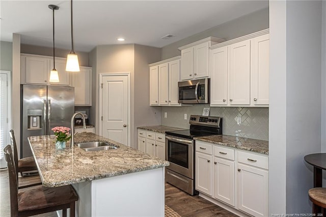 kitchen featuring appliances with stainless steel finishes, a sink, a breakfast bar, backsplash, and recessed lighting