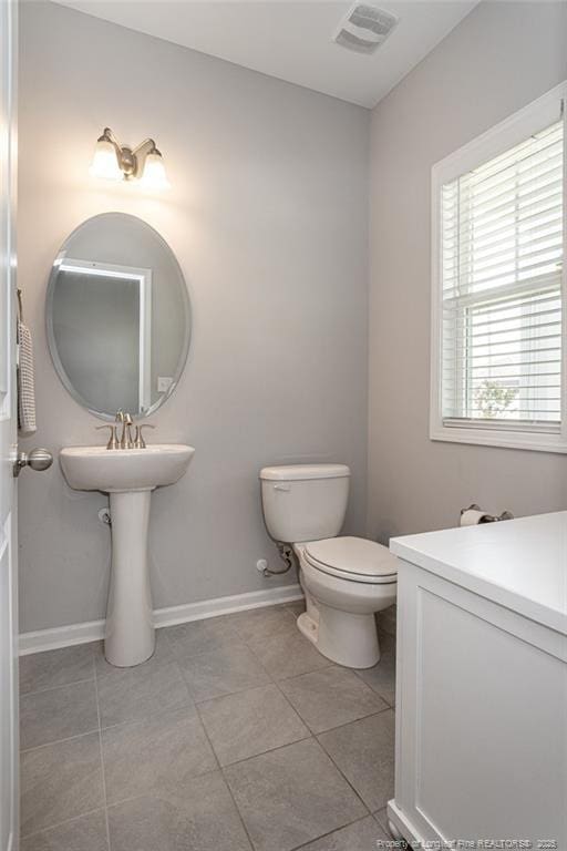 bathroom featuring toilet, tile patterned floors, and baseboards