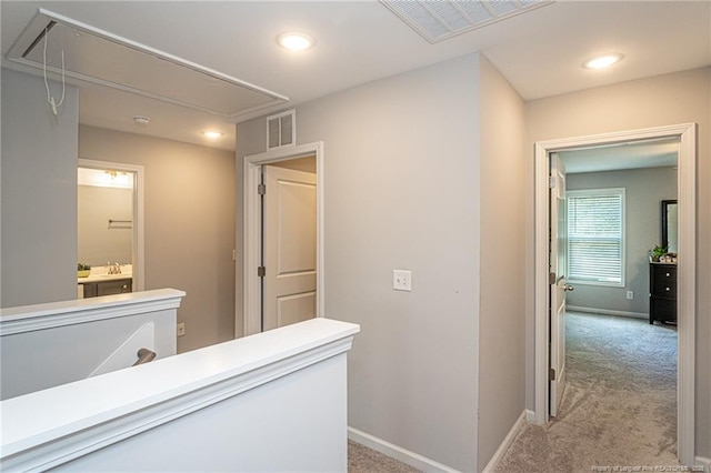 corridor featuring attic access, light carpet, baseboards, and recessed lighting