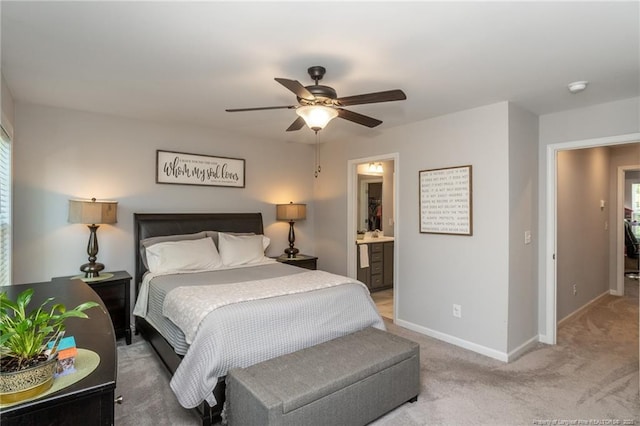 bedroom with baseboards, light carpet, a ceiling fan, and ensuite bathroom