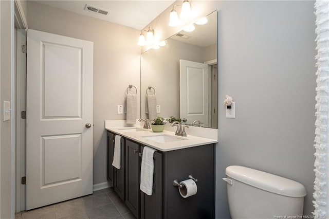 bathroom featuring toilet, tile patterned floors, and double vanity