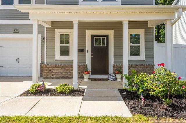 view of exterior entry featuring brick siding and covered porch