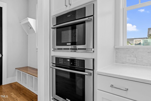 kitchen featuring stainless steel oven, plenty of natural light, and white cabinets