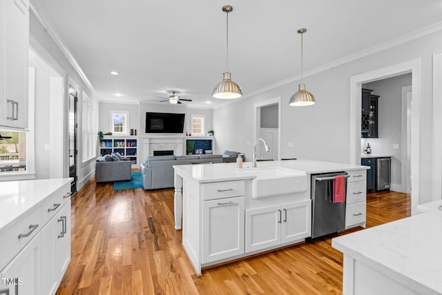 kitchen with a sink, dishwasher, ornamental molding, plenty of natural light, and light wood-type flooring