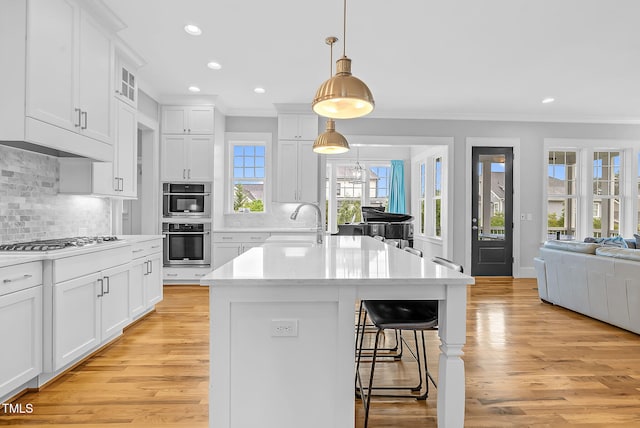 kitchen featuring crown molding, a sink, a breakfast bar area, light wood-style floors, and light countertops