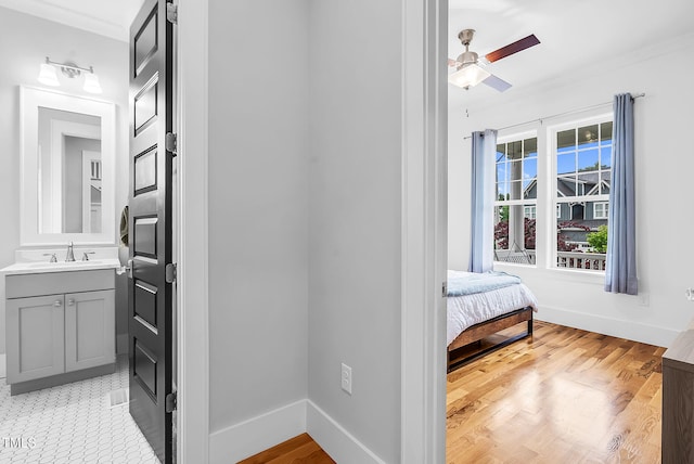 hallway featuring baseboards, a sink, and light wood finished floors