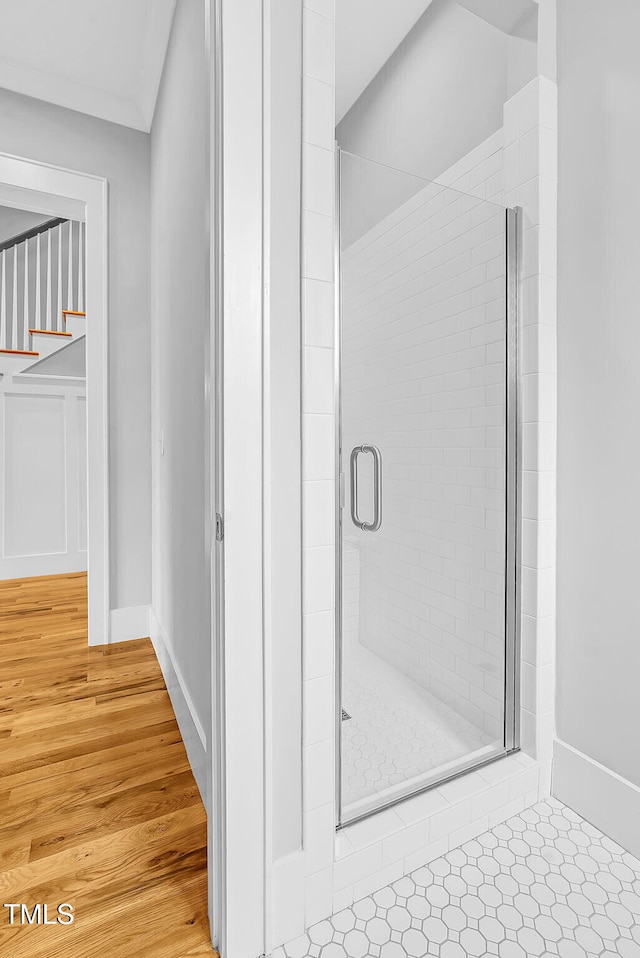 bathroom with a stall shower, wood finished floors, and baseboards