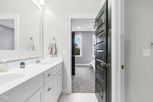 ensuite bathroom featuring double vanity, baseboards, and tile patterned floors