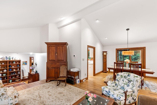 living room with high vaulted ceiling, light wood-style flooring, and baseboards