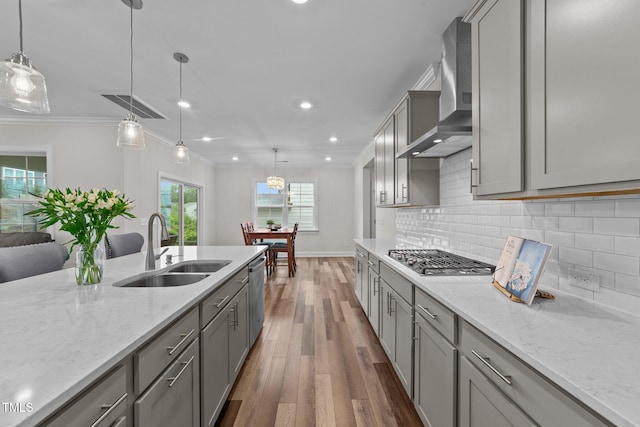 kitchen with a sink, gray cabinetry, stainless steel appliances, dark wood finished floors, and wall chimney exhaust hood