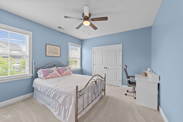carpeted bedroom featuring baseboards, multiple windows, an office area, and a ceiling fan