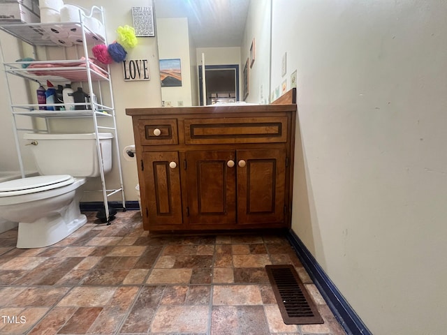 103 N Woods Rd, Henderson, NC 27536 - bathroom with stone tile flooring, baseboards, toilet, and vanity