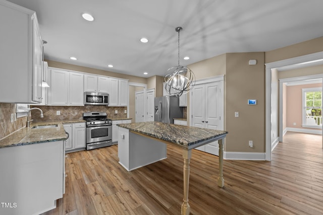 436 Edgepine Dr, Holly Springs, NC 27540 - kitchen featuring appliances with stainless steel finishes, a sink, light wood-type flooring, white cabinets, and light stone countertops