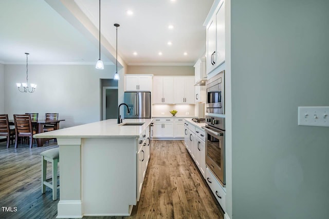 152 Chauncey Cir, Chapel Hill, NC 27516 - kitchen featuring stainless steel appliances, crown molding, wood finished floors, a chandelier, and a kitchen island with sink