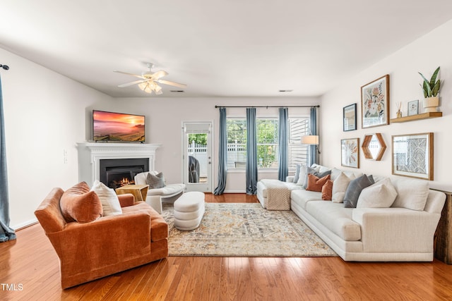 2635 Asher View Ct, Raleigh, NC 27606 - living area featuring a warm lit fireplace, ceiling fan, and wood finished floors