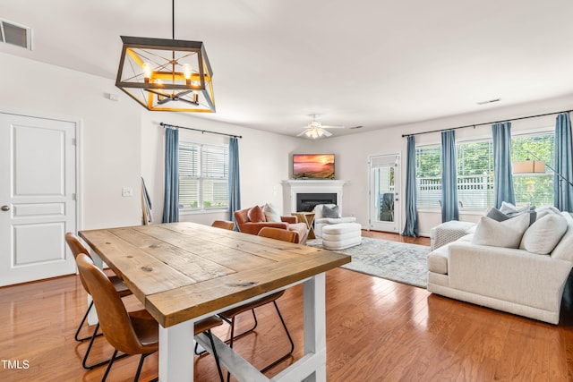2635 Asher View Ct, Raleigh, NC 27606 - dining room featuring plenty of natural light, light wood-type flooring, a chandelier, and a glass covered fireplace