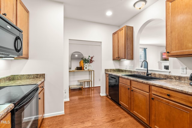 2635 Asher View Ct, Raleigh, NC 27606 - kitchen with black appliances, a sink, light wood finished floors, arched walkways, and brown cabinetry