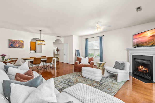 2635 Asher View Ct, Raleigh, NC 27606 - living room with arched walkways, wood finished floors, a fireplace with flush hearth, and a ceiling fan