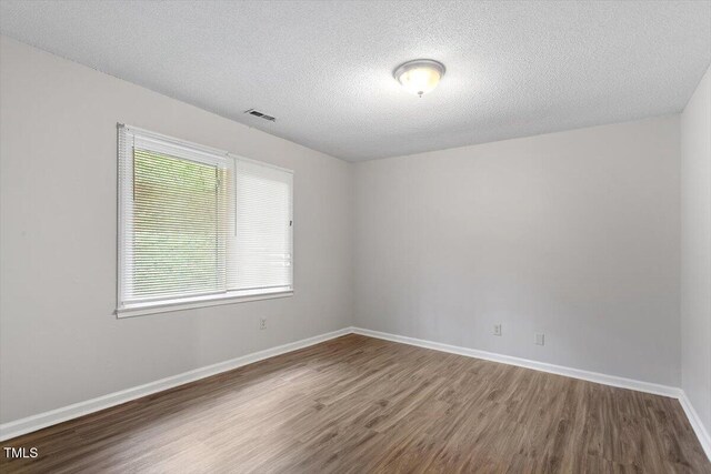 4812 Kaplan Dr, Raleigh, NC 27606 - unfurnished room with wood finished floors, a textured ceiling, and baseboards