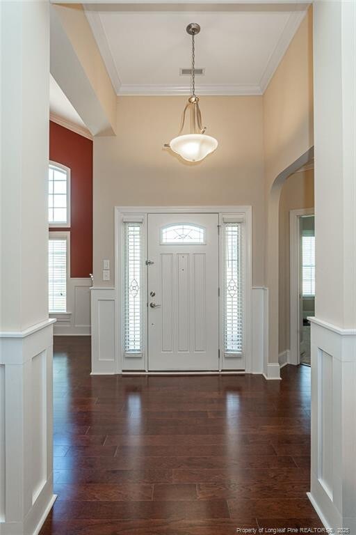 4222 Dock View Rd, Fayetteville, NC 28306 - foyer entrance with dark wood-type flooring, ornamental molding, wainscoting, arched walkways, and a decorative wall