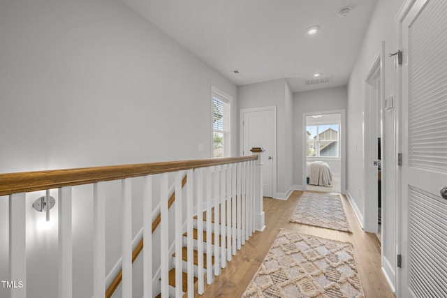 hall with light wood finished floors, baseboards, and recessed lighting