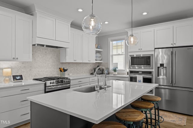 kitchen featuring appliances with stainless steel finishes, a sink, crown molding, a kitchen bar, and backsplash