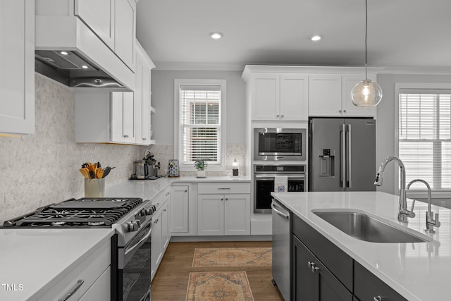 kitchen featuring stainless steel appliances, a sink, light countertops, crown molding, and white cabinets