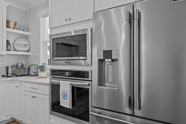 kitchen with stainless steel appliances, open shelves, healthy amount of natural light, and white cabinetry
