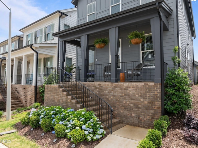 property entrance featuring a porch, board and batten siding, and brick siding