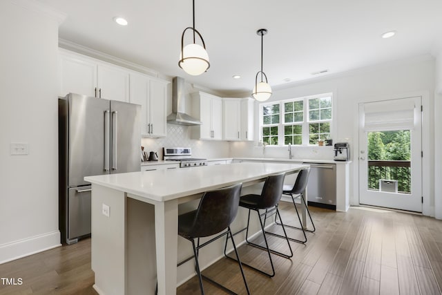 1602 Bowery Dr, Raleigh, NC 27607 - kitchen with wall chimney range hood, appliances with stainless steel finishes, a center island, decorative backsplash, and light countertops
