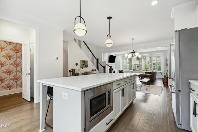 1602 Bowery Dr, Raleigh, NC 27607 - kitchen featuring appliances with stainless steel finishes, dark wood-style flooring, light countertops, a kitchen bar, and white cabinetry