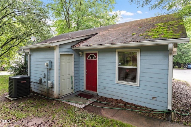 view of front facade featuring central AC unit and roof with shingles