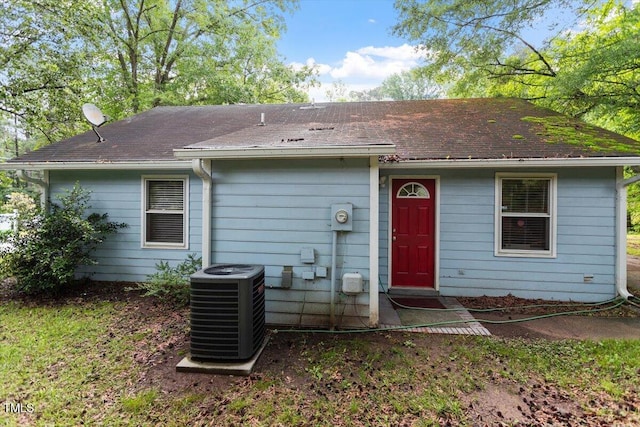 rear view of house featuring central AC and a shingled roof