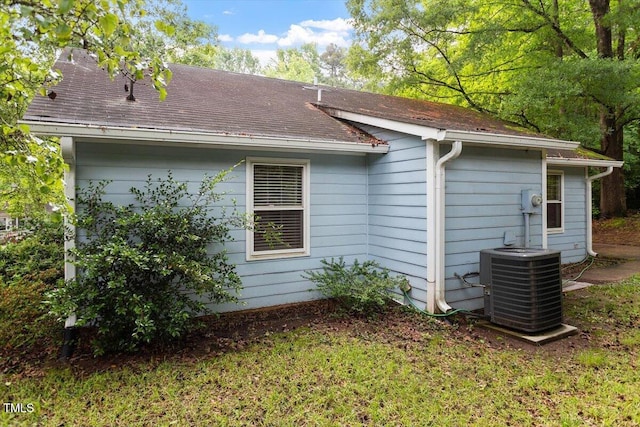 view of property exterior featuring cooling unit and roof with shingles