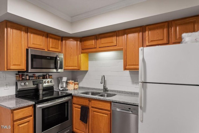 kitchen featuring appliances with stainless steel finishes, a sink, crown molding, decorative backsplash, and brown cabinets