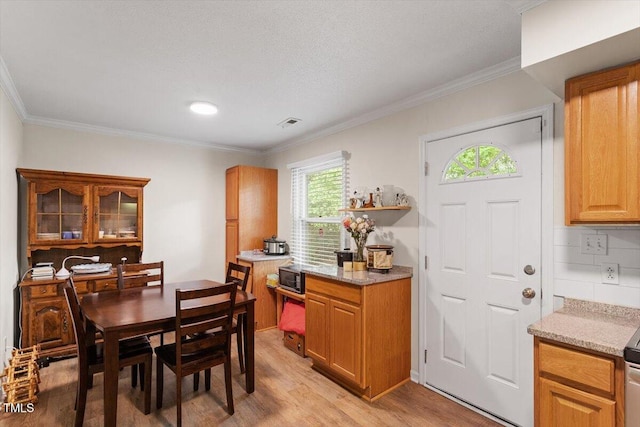 dining area featuring light wood-style floors and crown molding